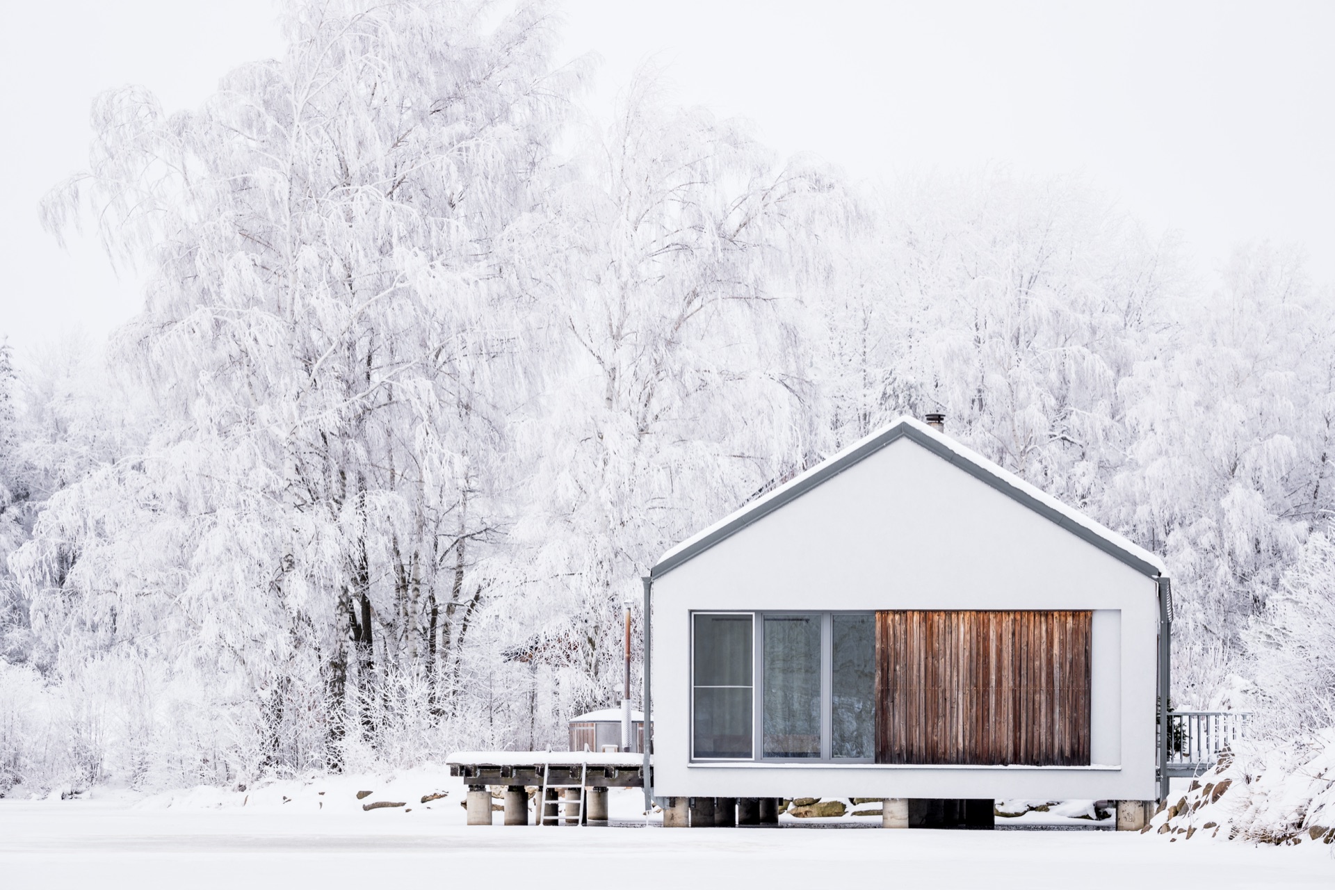 Snow-covered House on the Water with a hot tub by the frozen pond in winter